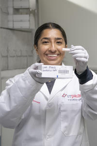 A woman stands with a sample in her hand