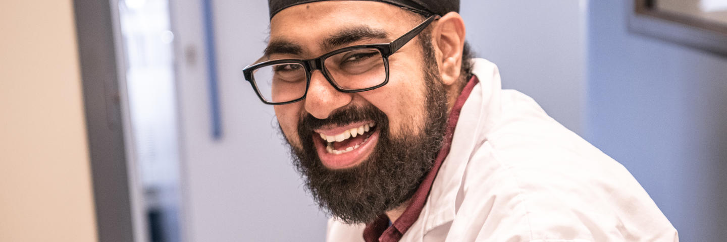 A man sitting at a desk smiles at the camera